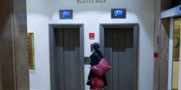 Mujer esperando el ascensor en la planta baja de una comunidad de vecinos