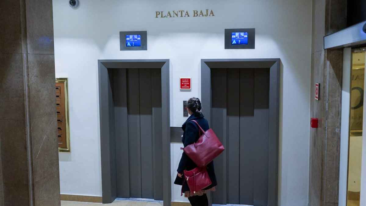 Mujer esperando el ascensor en la planta baja de una comunidad de vecinos