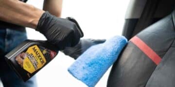 Persona aplicando limpiador de cuero Maddox en asiento de coche para restaurar brillo y proteger la tapicería.