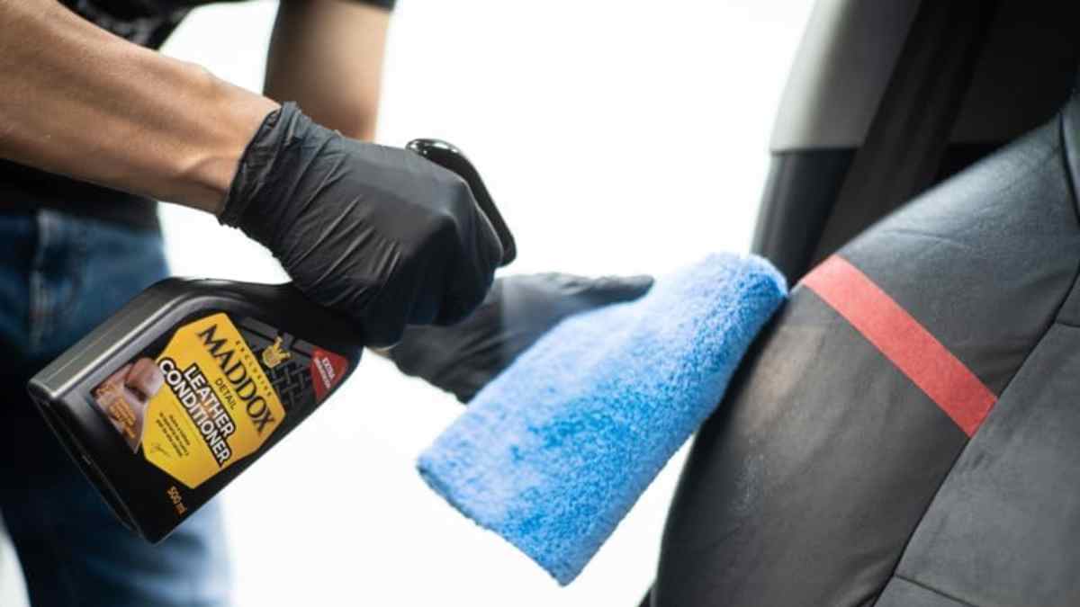 Persona aplicando limpiador de cuero Maddox en asiento de coche para restaurar brillo y proteger la tapicería.