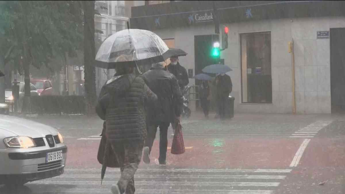 Personas con paraguas caminando bajo la lluvia en Madrid durante las lluvias pasajeras anunciadas por la Aemet.