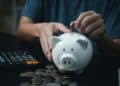 persona ahorrando dinero en una hucha mientras calcula su plan de pensiones.