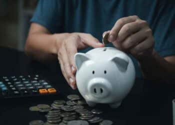 persona ahorrando dinero en una hucha mientras calcula su plan de pensiones.