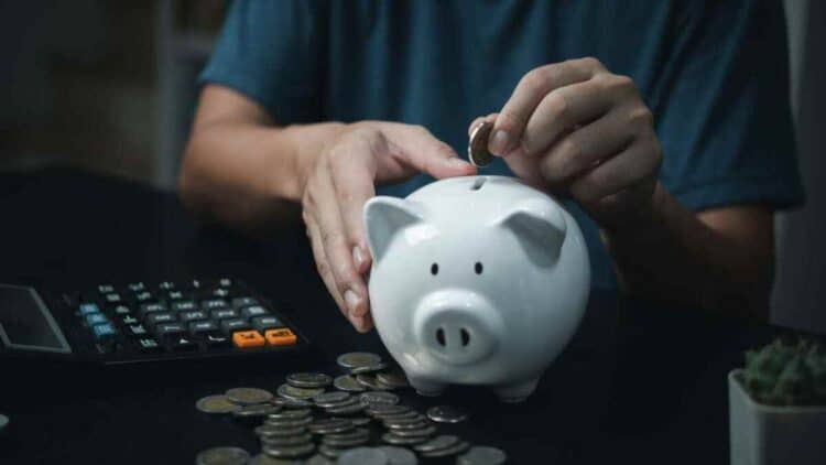 persona ahorrando dinero en una hucha mientras calcula su plan de pensiones.