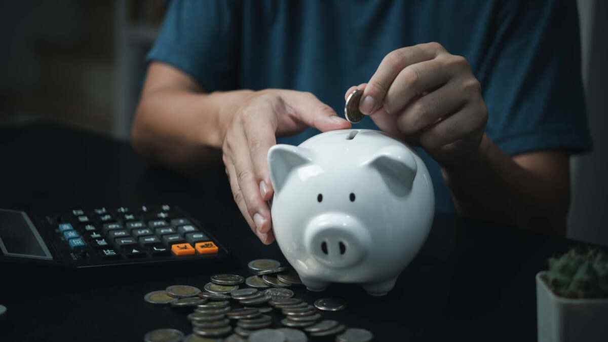persona ahorrando dinero en una hucha mientras calcula su plan de pensiones.