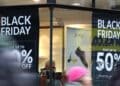 Escaparate con carteles de Black Friday 2025 anunciando descuentos del 50 por ciento en tiendas de España.