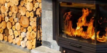 Chimenea encendida con leña apilada en casa durante el invierno en el Reino Unido.
