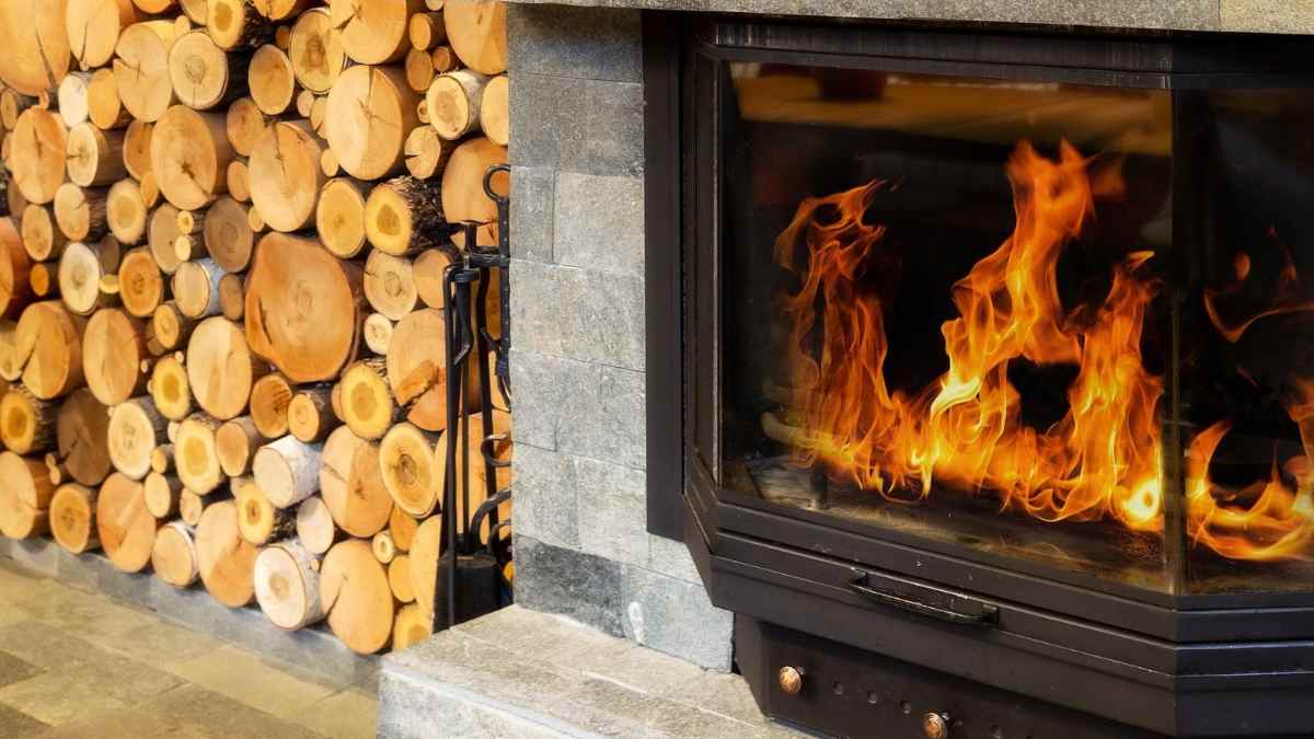 Chimenea encendida con leña apilada en casa durante el invierno en el Reino Unido.