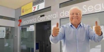 Jubilado feliz frente a la Tesorería General de la Seguridad Social tras aumento de pensión mínima por cambio familiar.