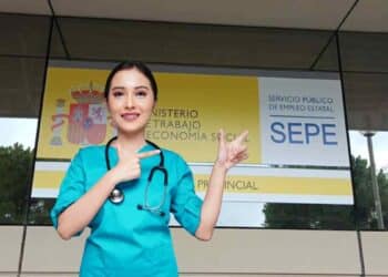 Trabajadora sanitaria frente a una oficina del SEPE con cartel del Ministerio de Trabajo.