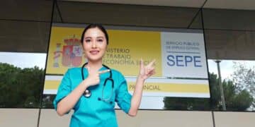 Trabajadora sanitaria frente a una oficina del SEPE con cartel del Ministerio de Trabajo.