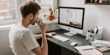 Hombre trabajando desde casa en ordenador por ofertas de empleo remoto del SEPE con contrato indefinido y sueldos de hasta 1.800 euros.