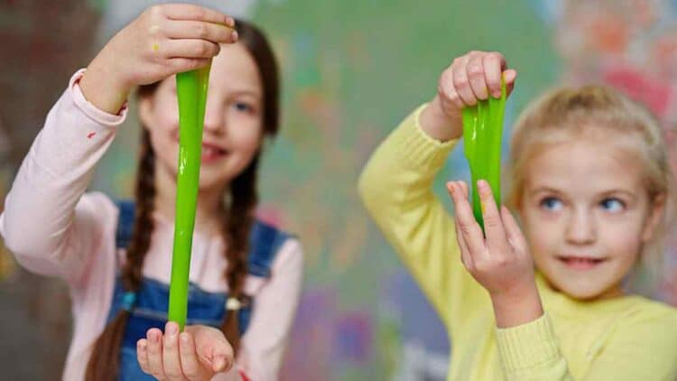 niñas jugando con slime verde casero hecho con cola blanca, detergente y colorante.