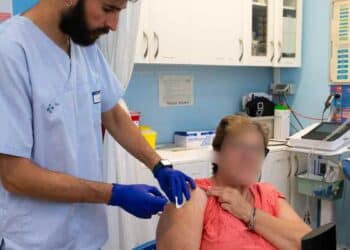 Profesional sanitario vacunando a una mujer mayor contra la gripe en Madrid campaña 2025-2026.