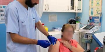 Profesional sanitario vacunando a una mujer mayor contra la gripe en Madrid campaña 2025-2026.