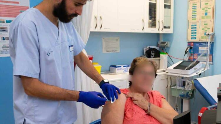 Profesional sanitario vacunando a una mujer mayor contra la gripe en Madrid campaña 2025-2026.
