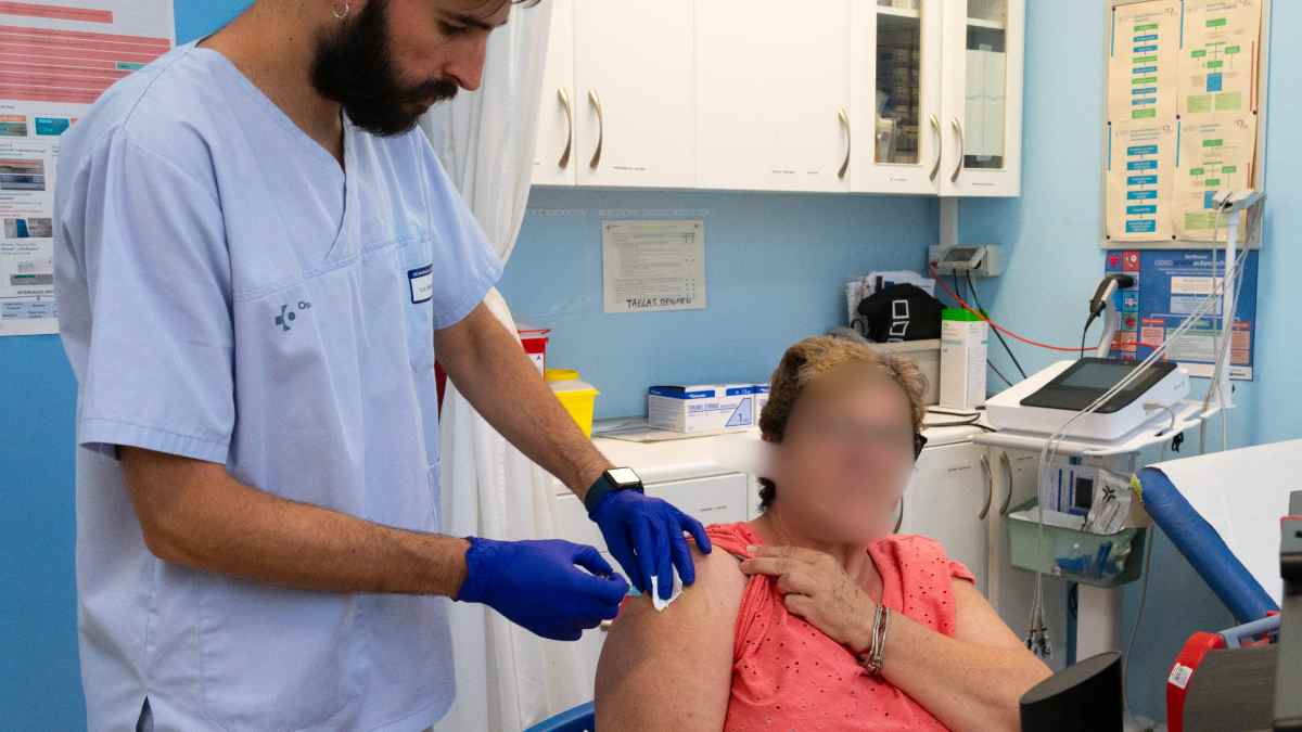 Profesional sanitario vacunando a una mujer mayor contra la gripe en Madrid campaña 2025-2026.