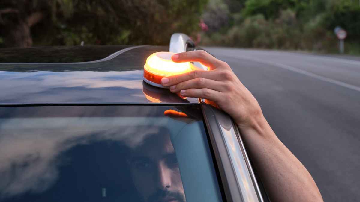 Conductor colocando la baliza V16 obligatoria en el coche según la DGT
