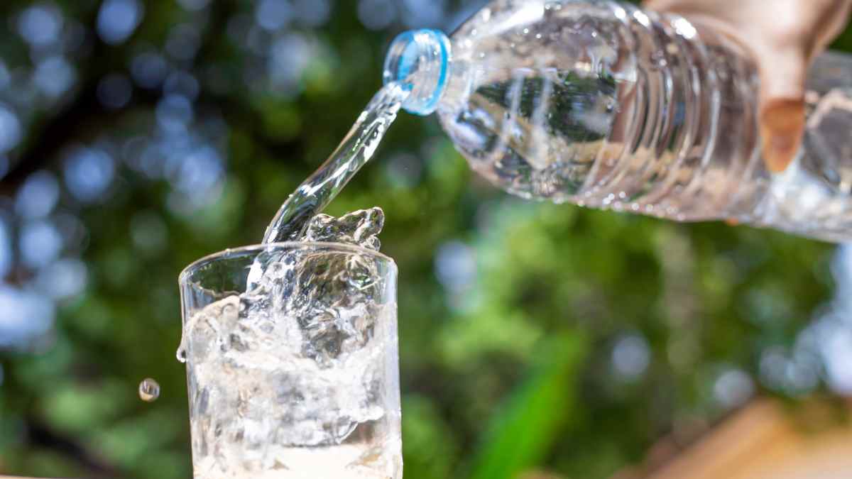 Agua embotellada sirviéndose en un vaso en una noticia sobre alerta por Pseudomonas aeruginosa.