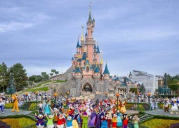 Personajes Disney frente al castillo de Disneyland París durante un desfile en el parque temático.