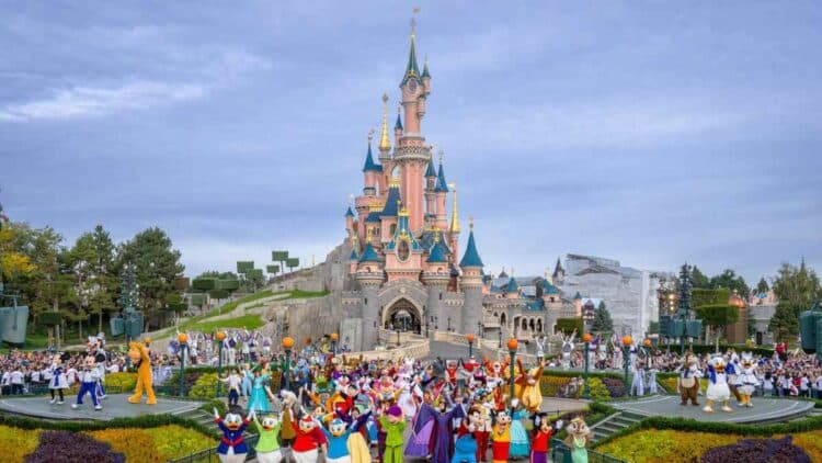 Personajes Disney frente al castillo de Disneyland París durante un desfile en el parque temático.