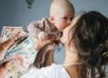 madre con bebé y dinero representando ayuda por maternidad de Hacienda