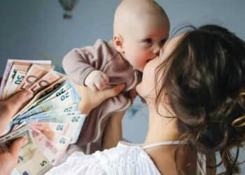 madre con bebé y dinero representando ayuda por maternidad de Hacienda