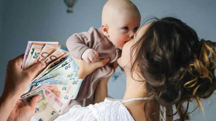 madre con bebé y dinero representando ayuda por maternidad de Hacienda