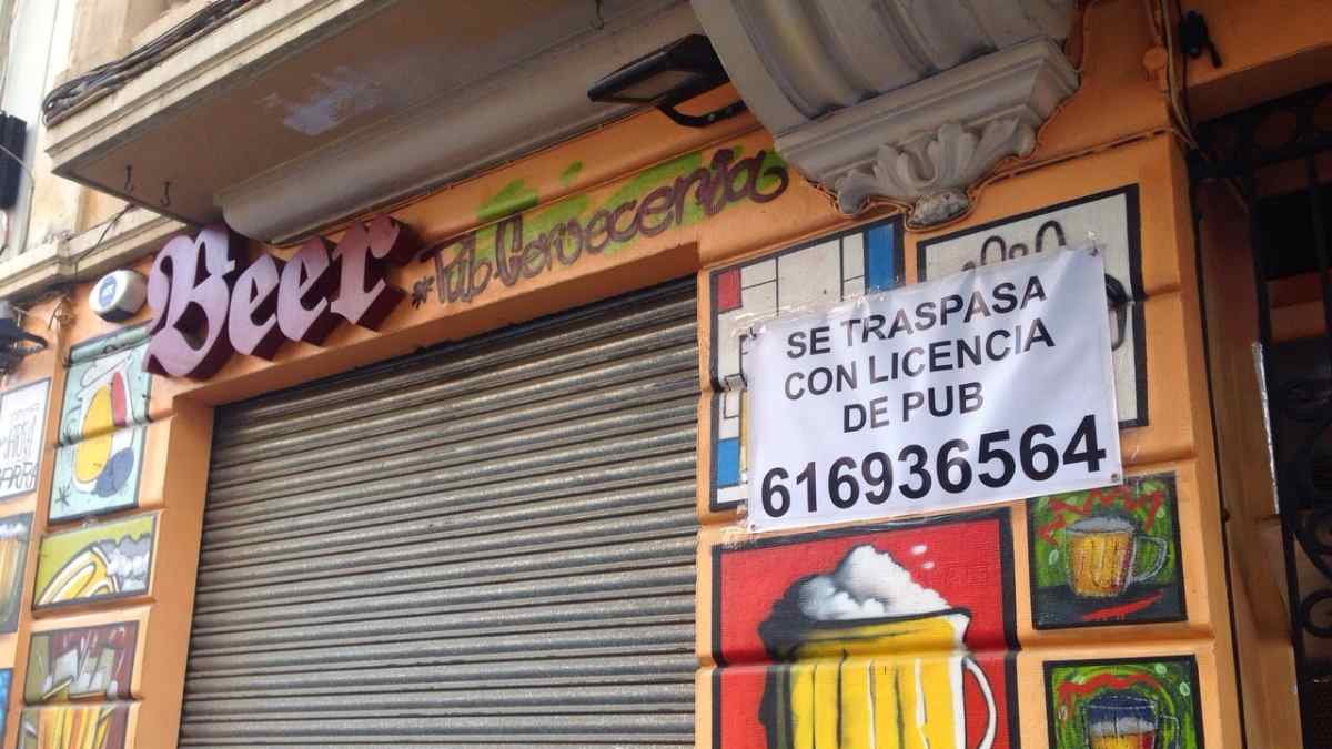 Fachada de un pub cerrado con cartel de traspaso en Getafe.