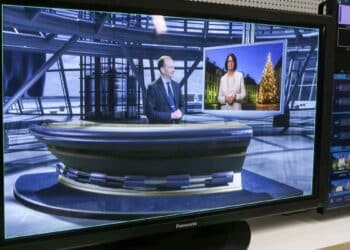 Presentadores en plató de televisión durante emisión de informativo por cable.