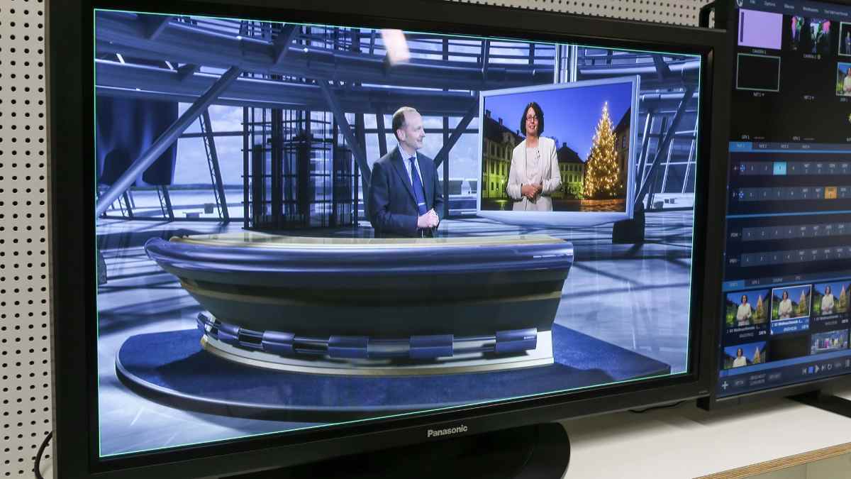 Presentadores en plató de televisión durante emisión de informativo por cable.