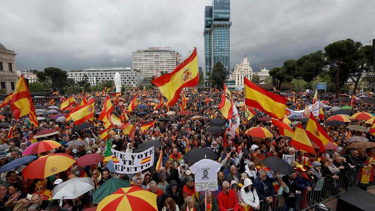 Multitud con banderas de España durante una manifestación en una gran avenida de Madrid.