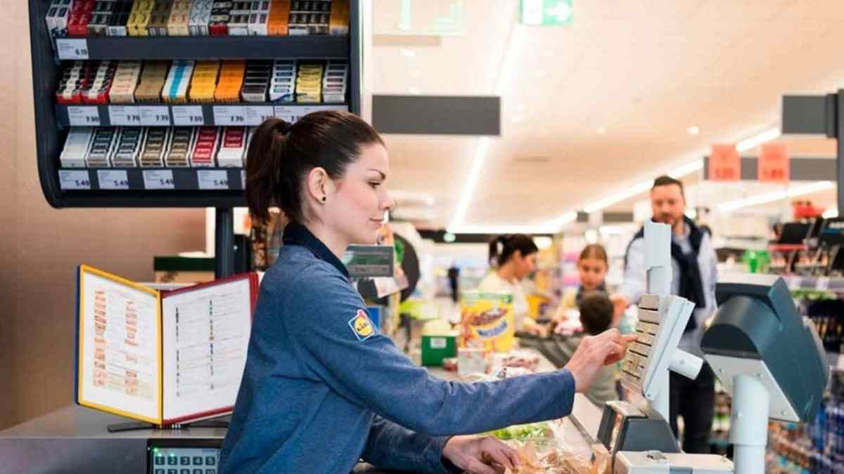 Cajera de supermercado atendiendo en la línea de caja durante su jornada laboral.