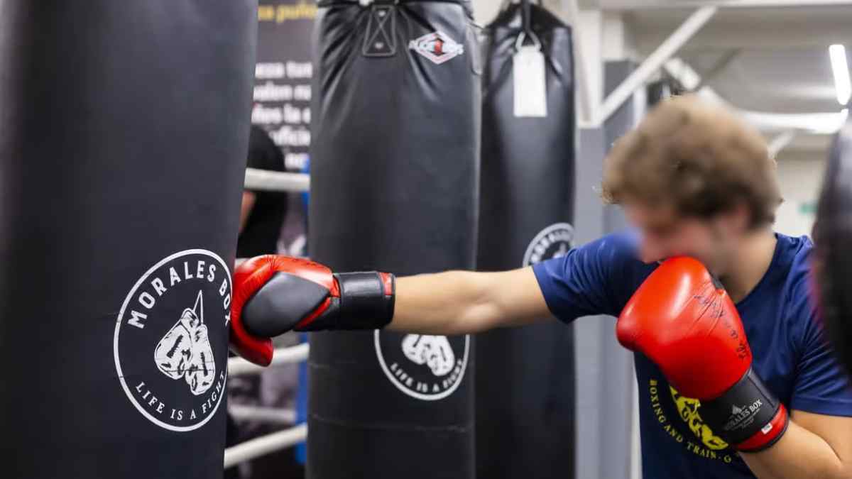 Trabajador dando un golpe a un saco de boxeo durante un entrenamiento en gimnasio.