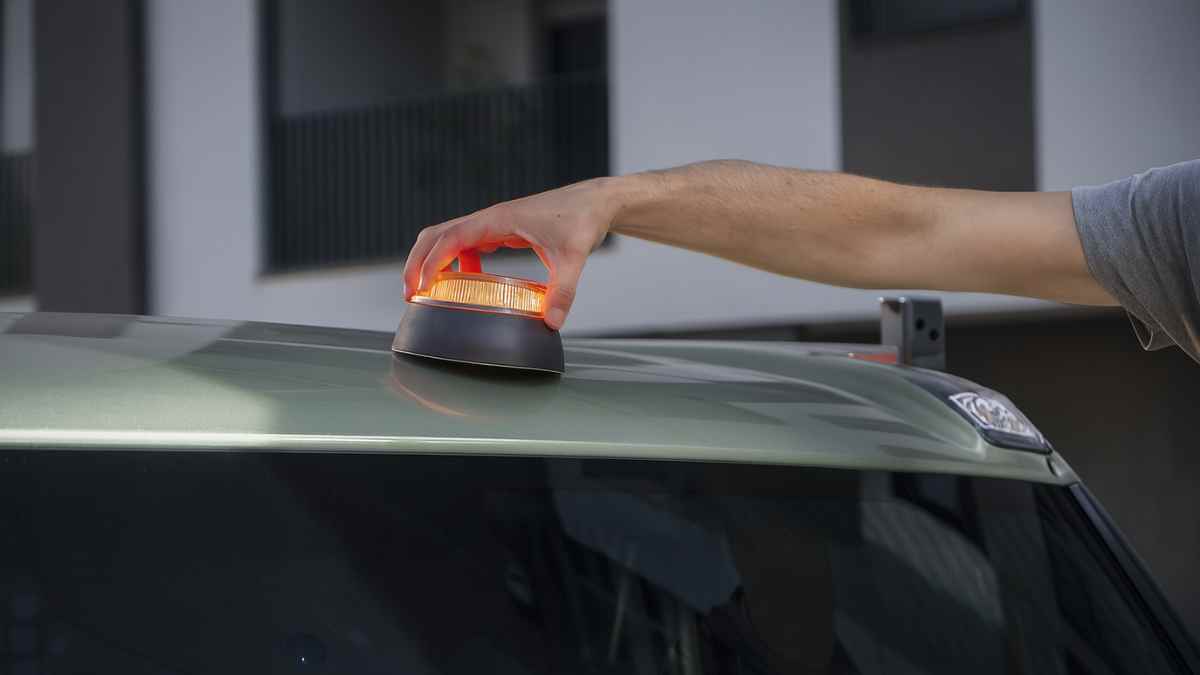 Colocación de una baliza V16 conectada en el techo de un coche.