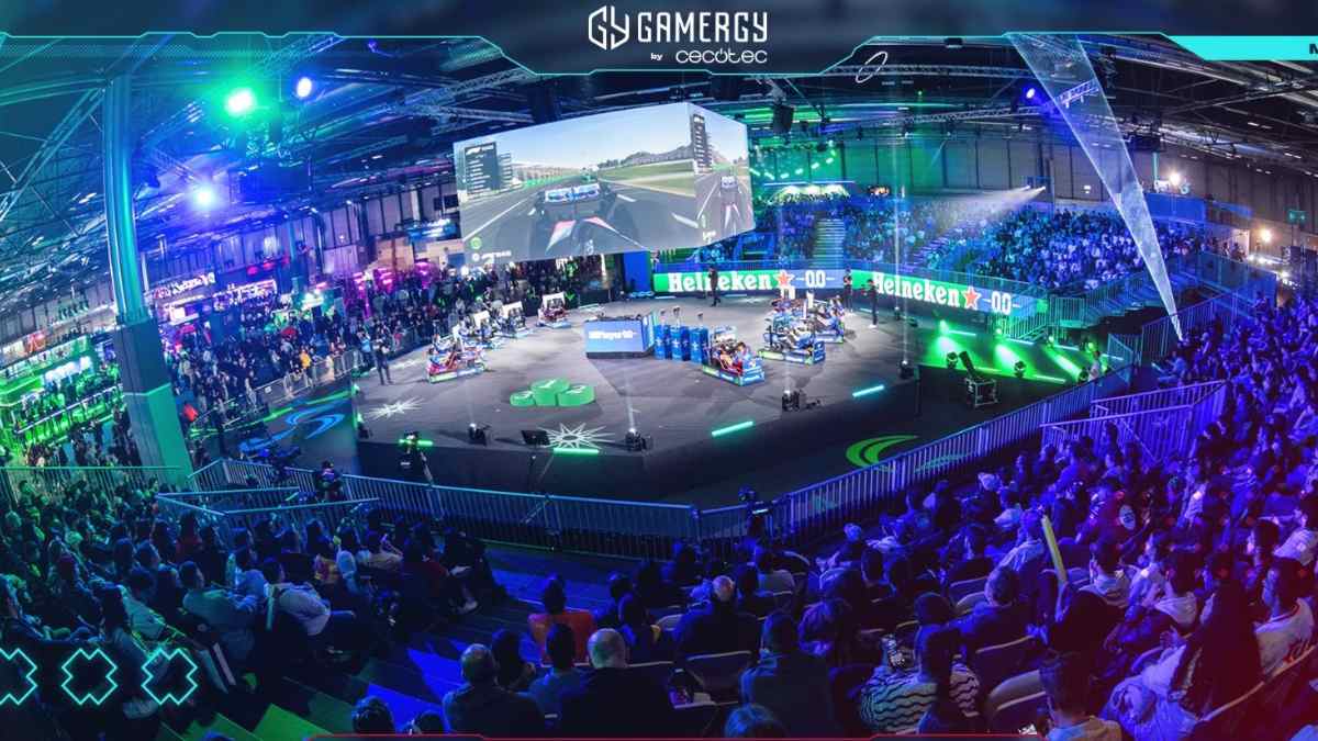 Panorámica de GAMERGY 2025 en IFEMA Madrid con público, simuladores y escenario iluminado.