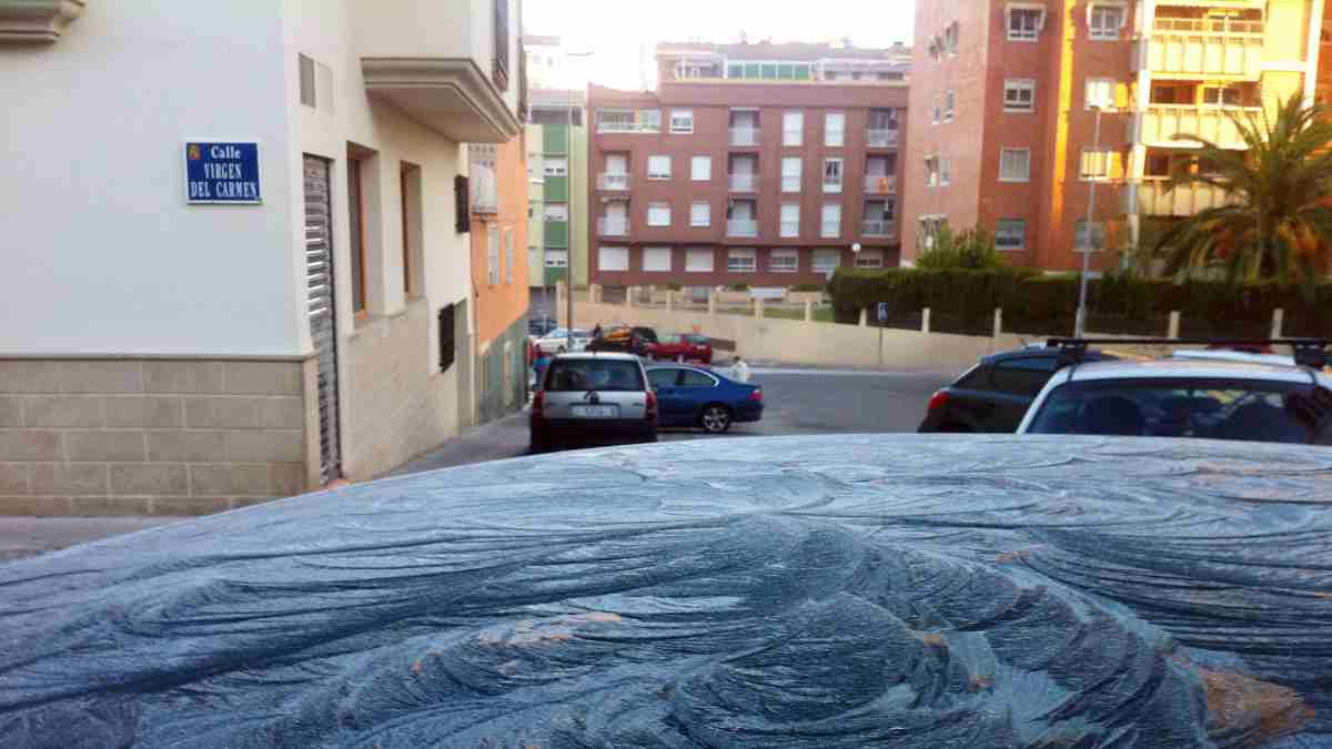 Coche con escarcha matinal en una calle urbana durante una helada.