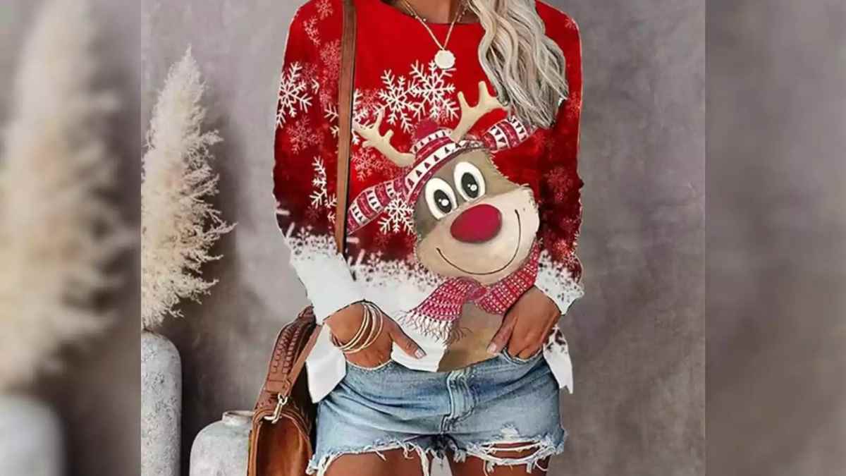 Mujer con jersey navideño rojo con reno y copos de nieve disponible en Amazon por menos de 20 euros.
