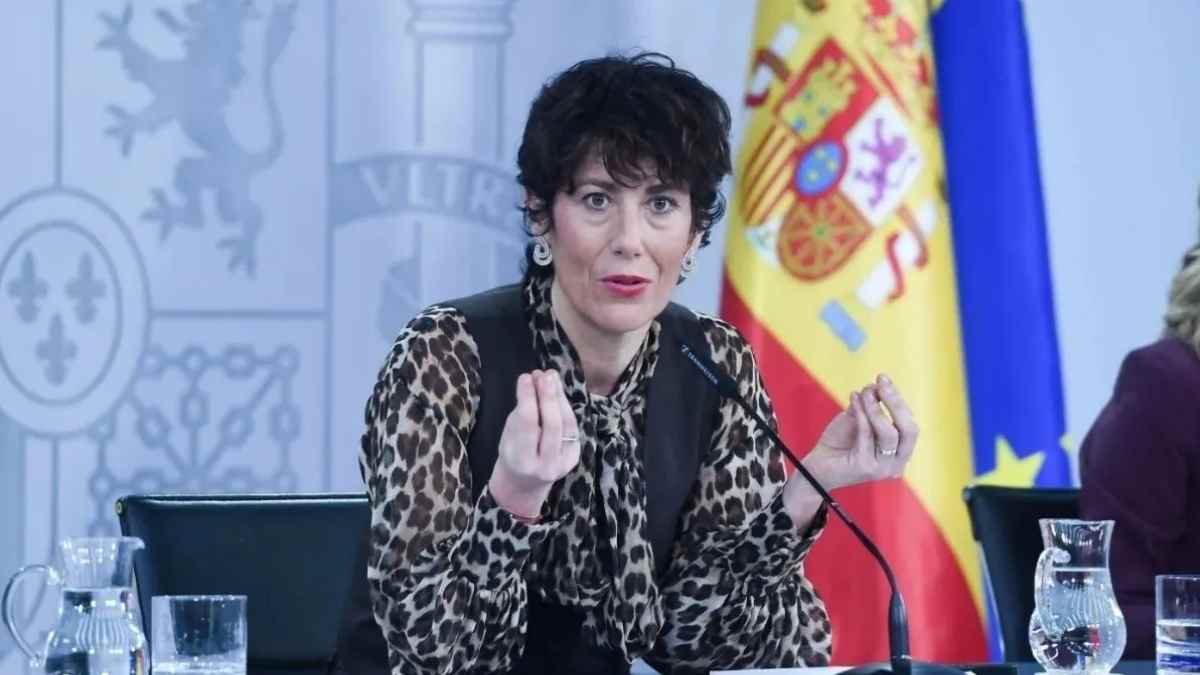 Elma Sáiz en rueda de prensa sobre pensiones con banderas de España y la Unión Europea de fondo.
