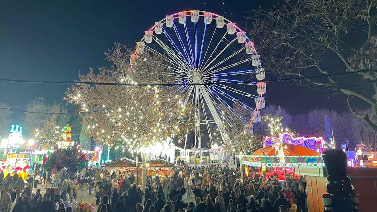 Noria iluminada y ambiente navideño en Navipark de Móstoles durante la noche.
