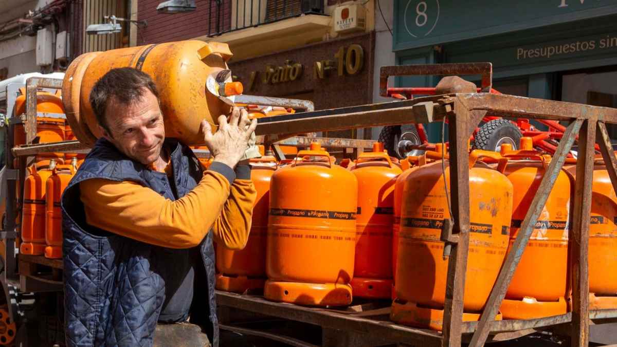 Repartidor transportando bombonas de butano durante el reparto en la calle.