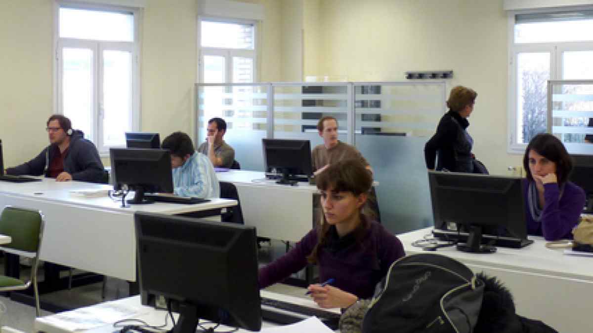 Aspirantes estudiando en un aula con ordenadores para preparar oposiciones en España.