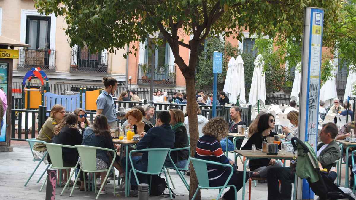 Terraza de hostelería en Madrid con clientes en una plaza al aire libre.