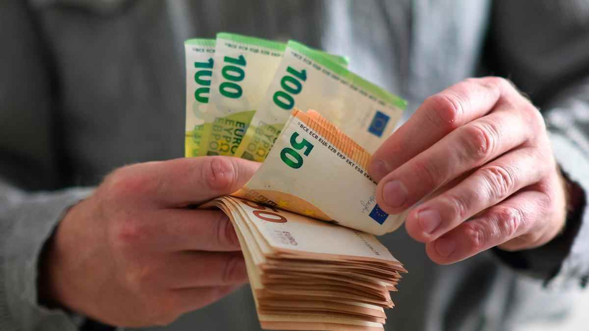 Persona contando billetes de euros relacionada con la paga extra de pensiones 2025.