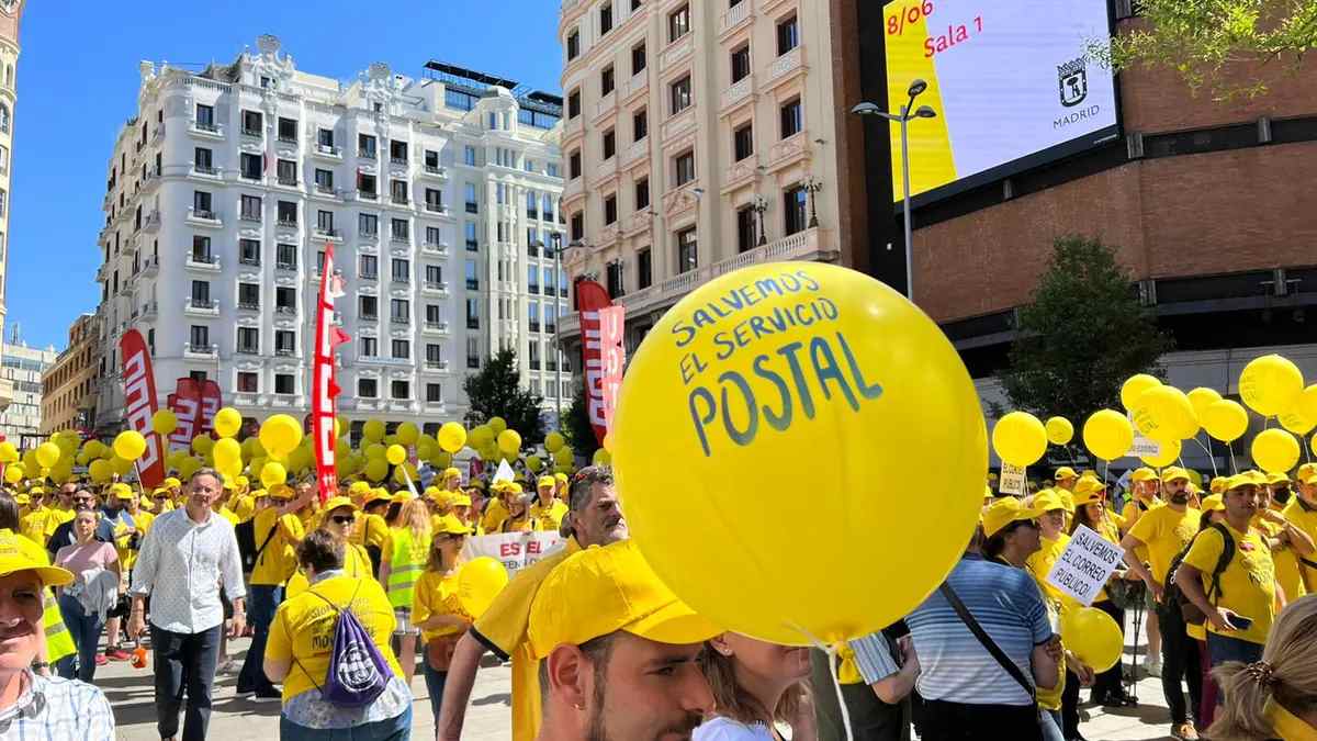 Manifestación de trabajadores de Correos en Madrid con globos amarillos reclamando la protección del servicio postal.