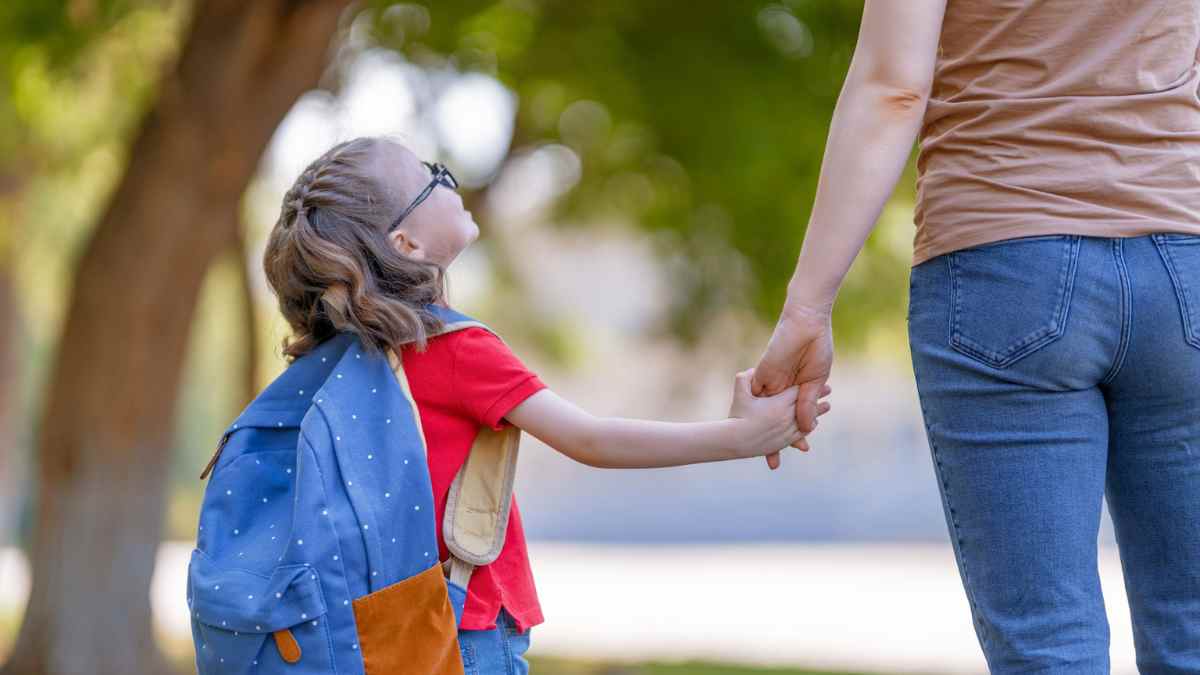 Madre llevando de la mano a su hija al colegio, ejemplo del permiso por fuerza mayor para cuidar hijos enfermos.