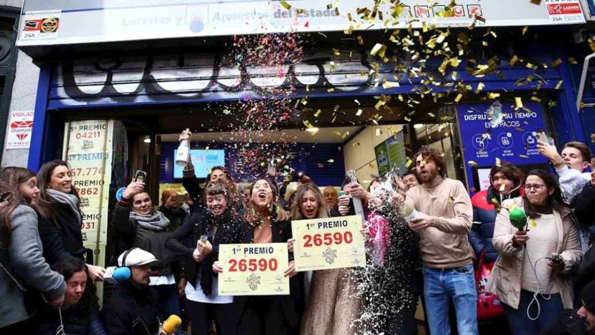 Ganadores celebran el premio del Gordo de la Lotería de Navidad frente a una administración de Loterías.