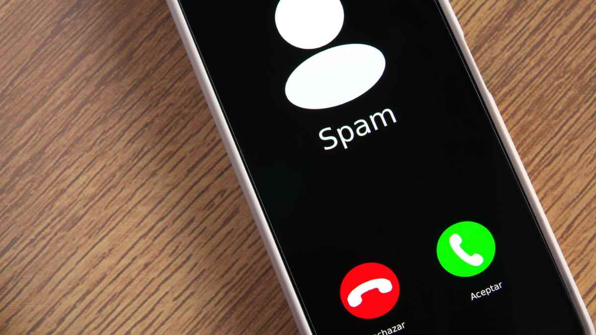 Llamada de spam mostrada en la pantalla de un móvil sobre una mesa.