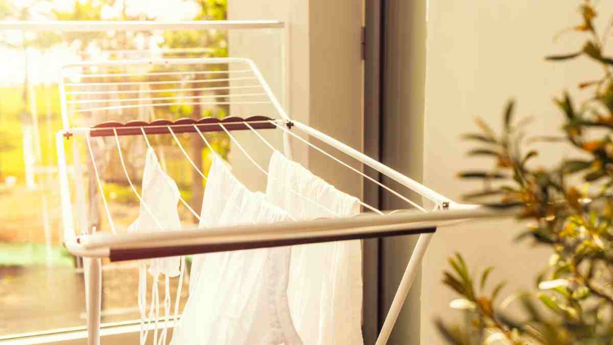 Tendedero eléctrico con ropa secándose en interior durante un día lluvioso.