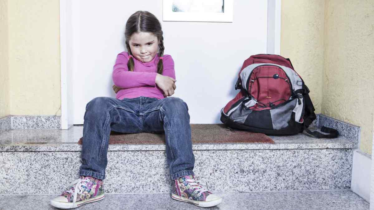 Niña esperando sentada con mochila junto a la puerta tras la decisión del Tribunal Supremo sobre el caso de abandono.